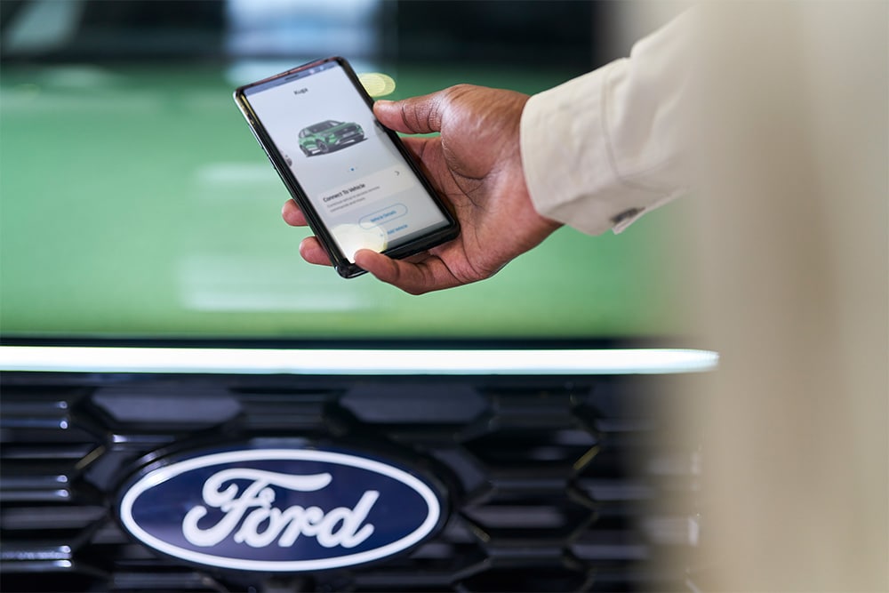 Femme regardant un smartphone avec l’application Ford affichée