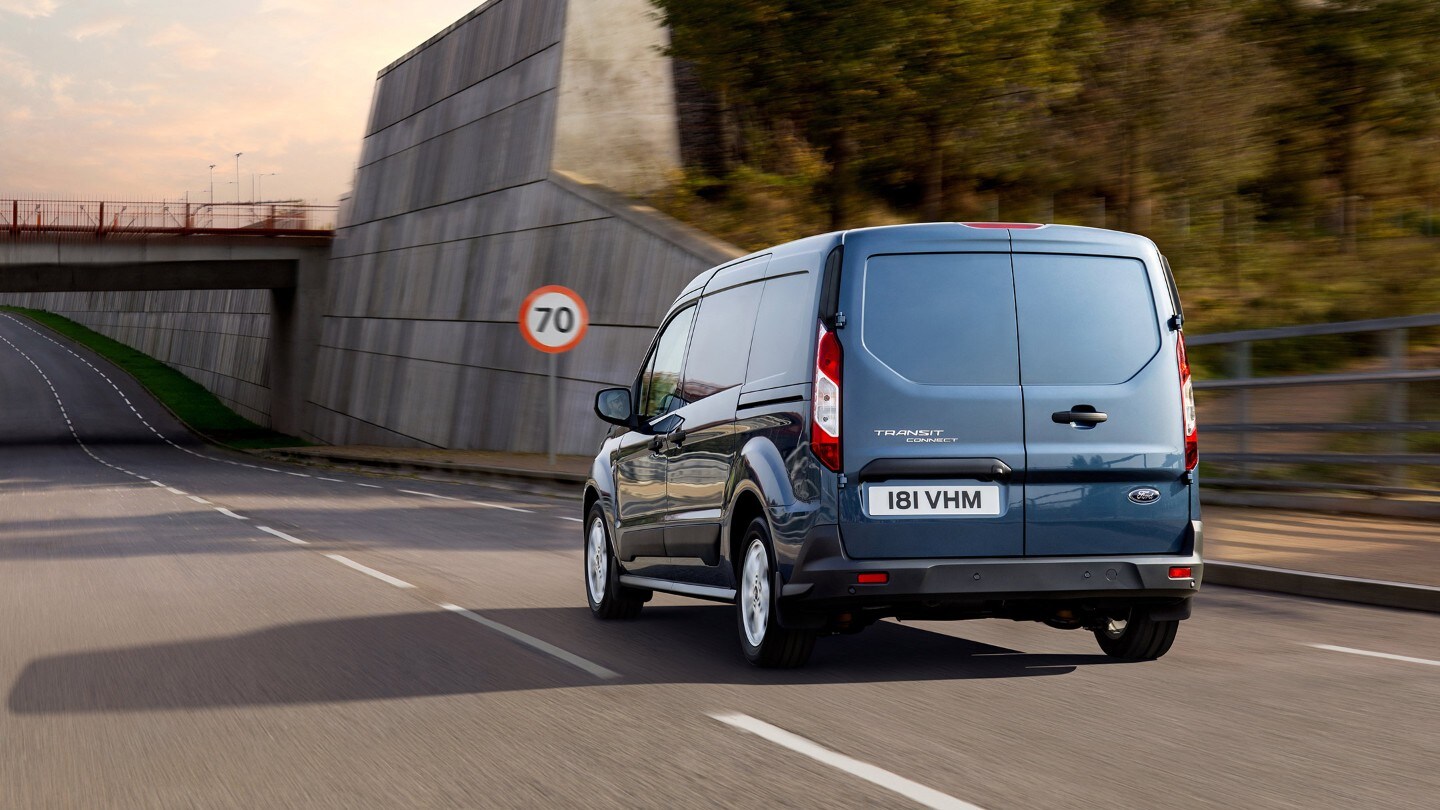 Vue arrière du Ford Transit Connect sur route, devant un panneau de signalisation.