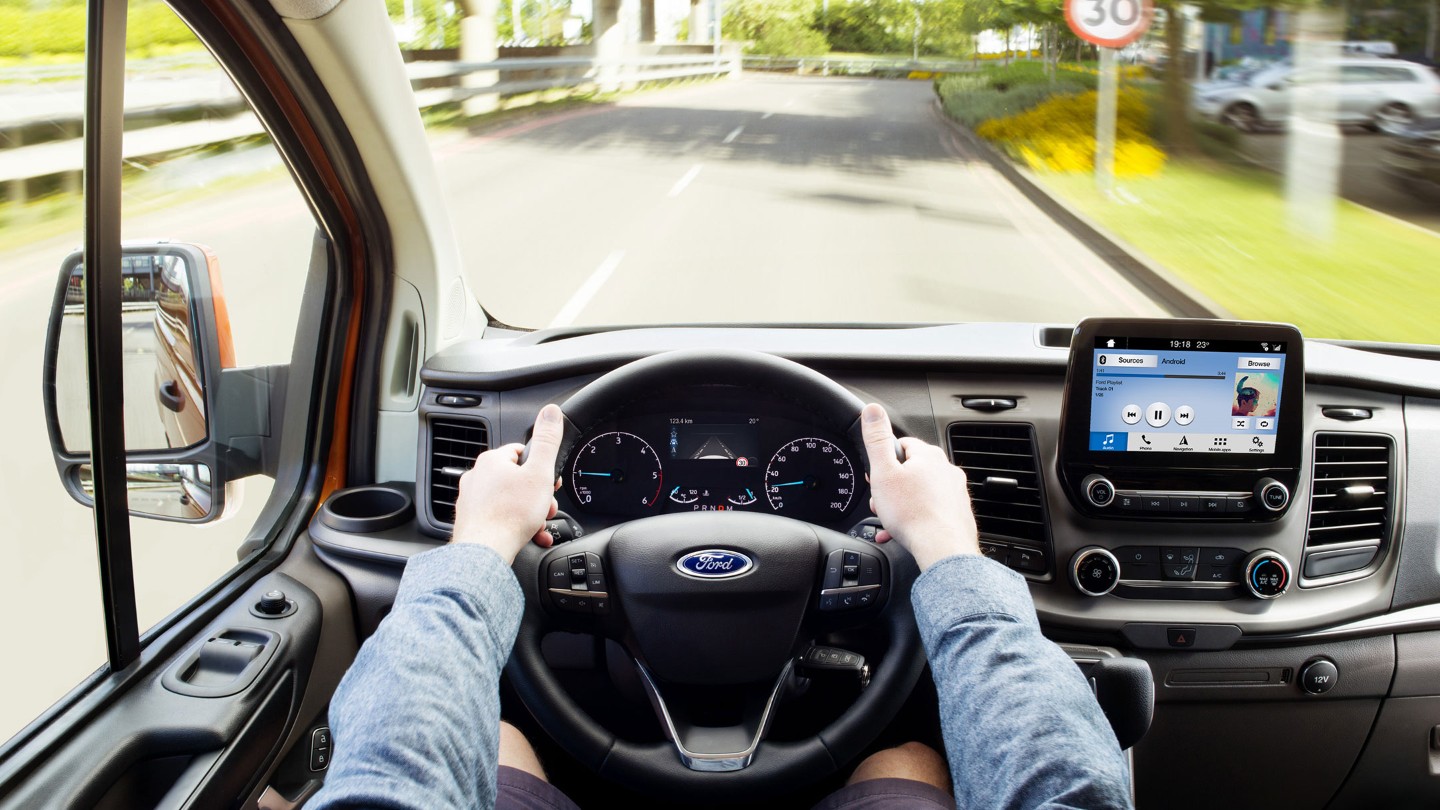 Vue intérieure du Transit Custom avec le volant et l’écran SYNC 3. 