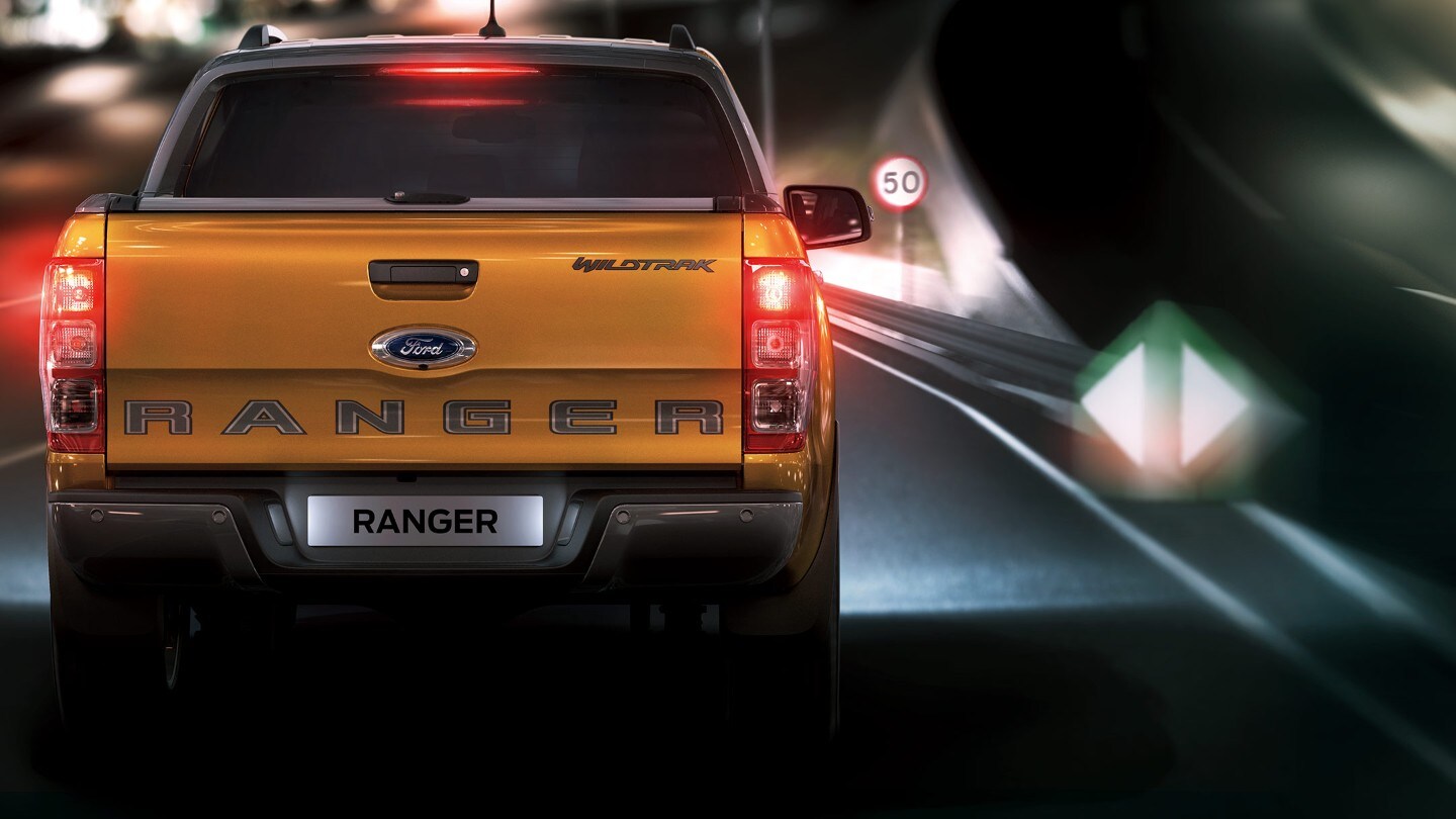 Vue arrière du Ford Ranger sur route  avec un panneau de signalisation en arrière plan.