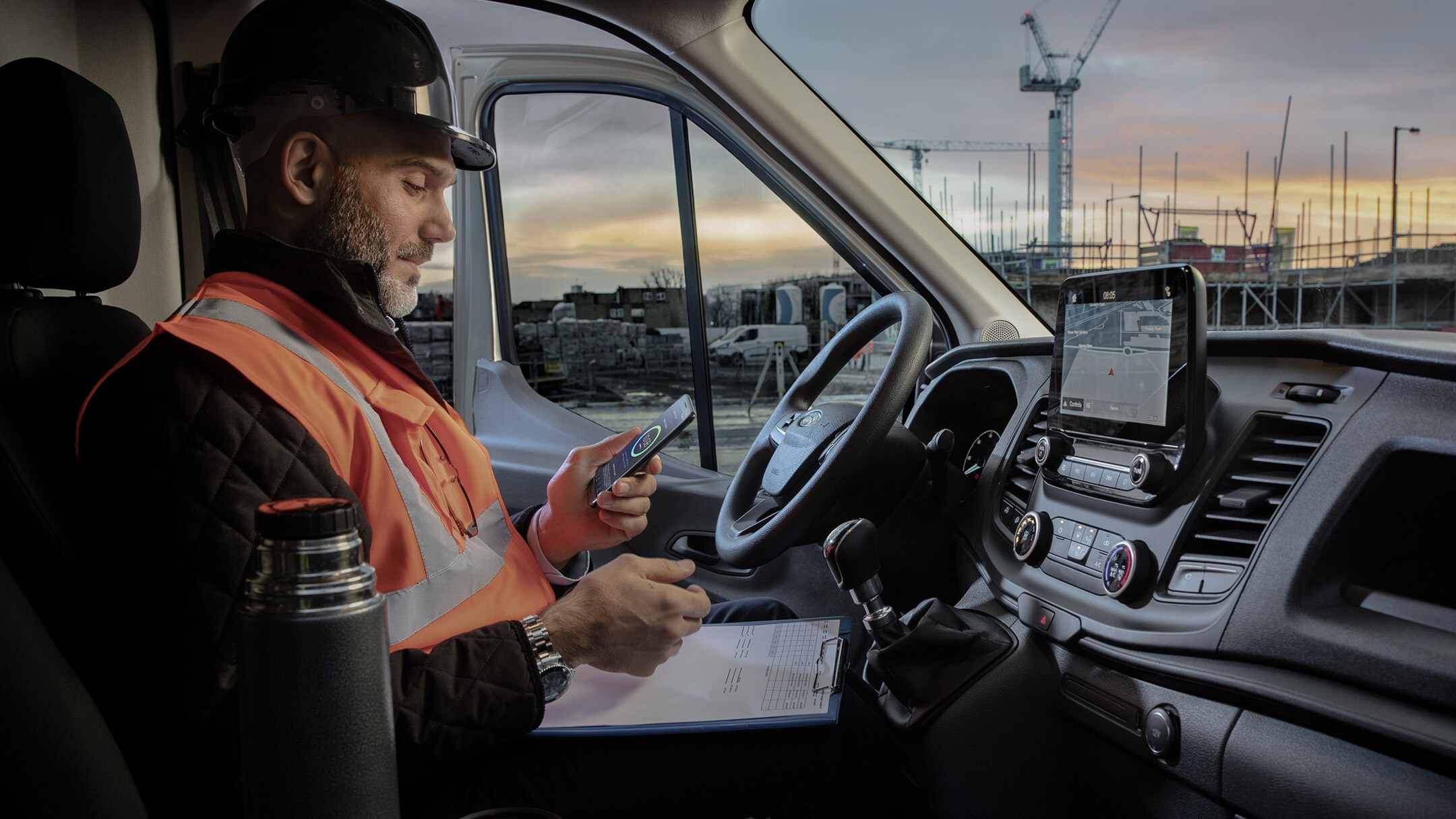 Vue intérieure du Ford Transit avec un homme tenant un smartphone.