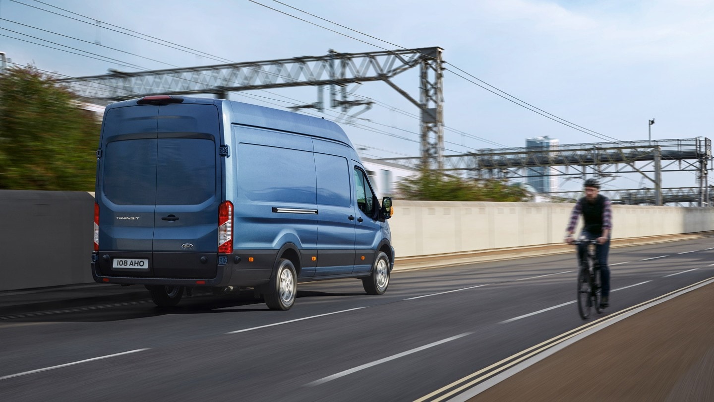 Vue arrière du Ford Transit 2T Bleu roulant sur la route