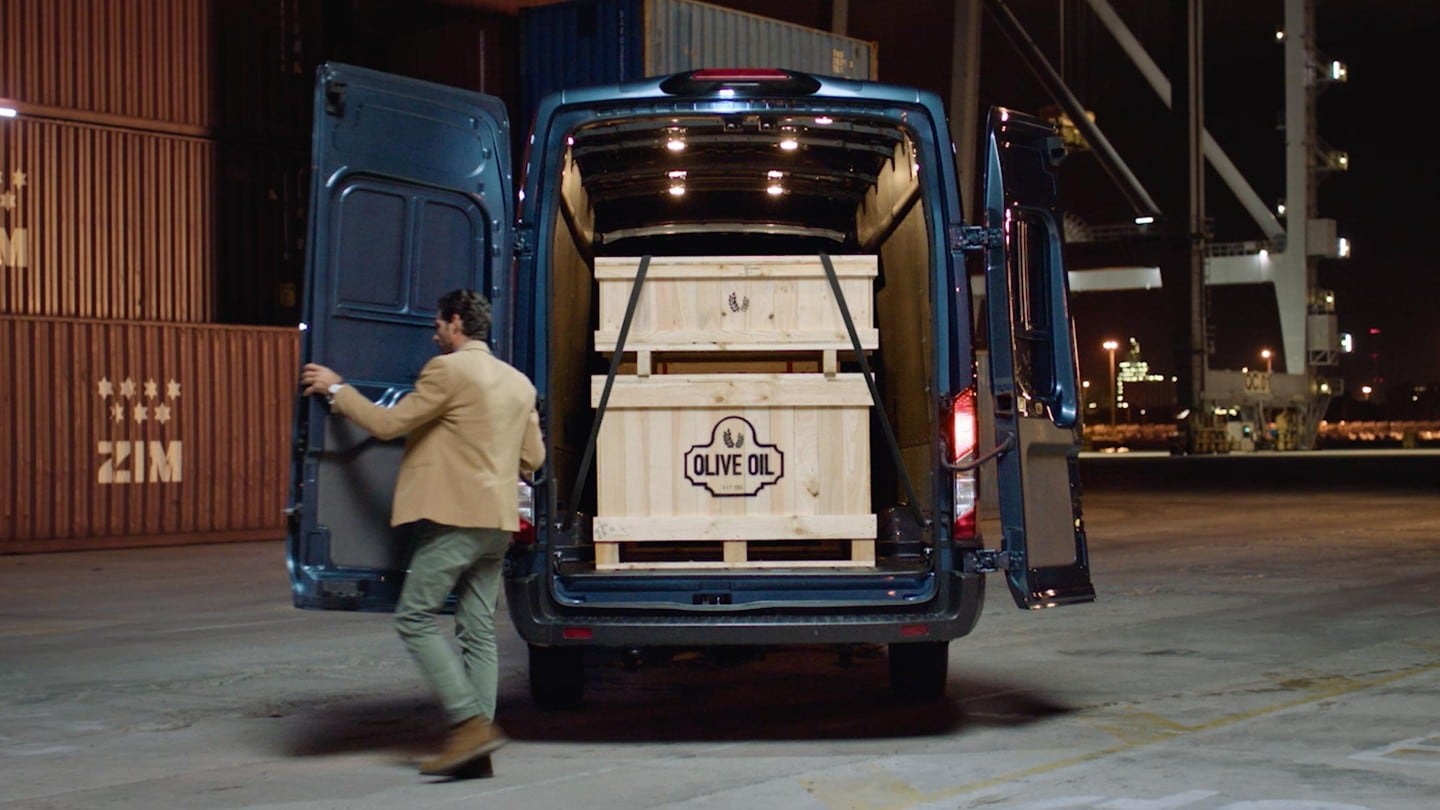 Vue arrière du Ford Transit, son chargement et son conducteur. 