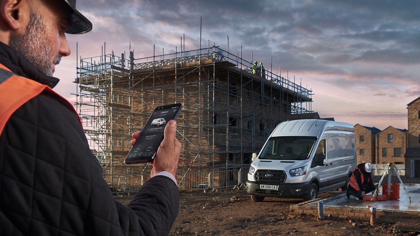 Un homme regarde son téléphone portable sur un chantier de construction avec le Ford Transit