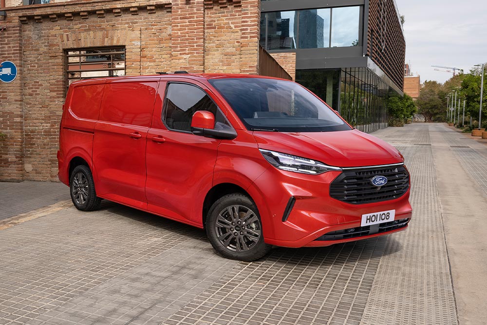 Fourgon Ford Transit Custom rouge stationné dans la rue.