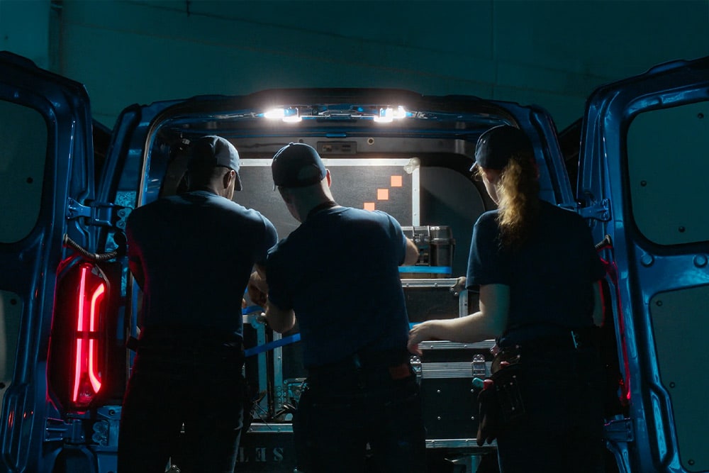 Trois personnes travaillant à l’arrière d’un fourgon électrique Ford E-Transit Custom.