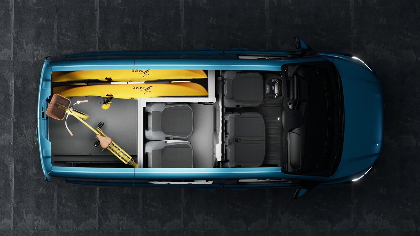L'intérieur d'un Ford Transit Custom avec des kayaks et des vélos.