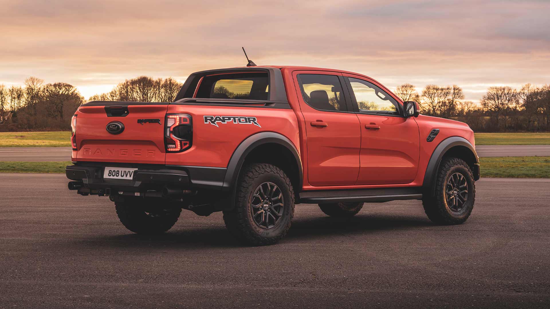 Vue arrière d’un Ford Ranger Raptor Code Orange garé sur une piste.