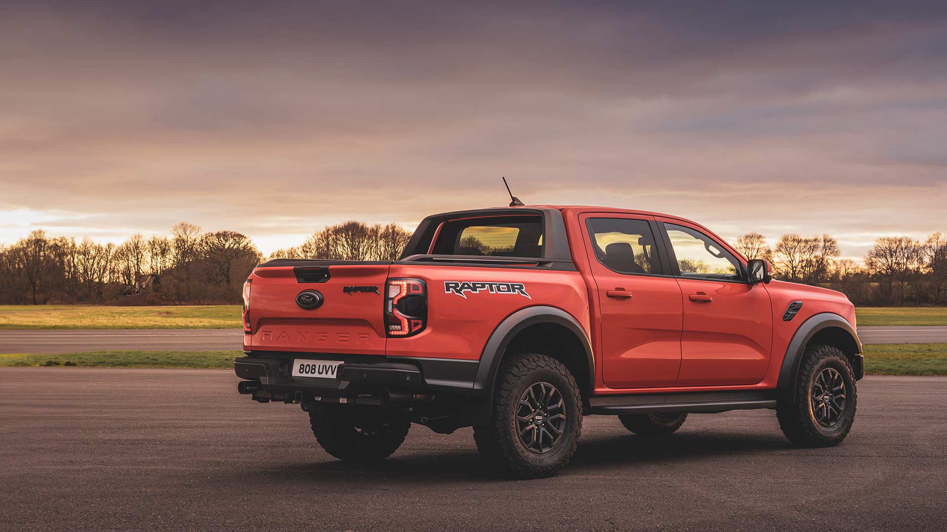 Vue arrière d’un Ford Ranger Raptor Code Orange roulant sur une piste.