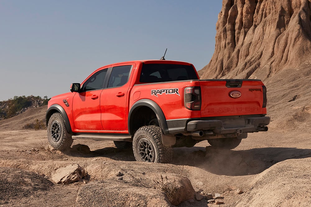 Ford Ranger Raptor Code Orange en montée sur des rochers.