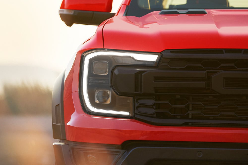 Gros plan des phares et de la calandre d’un Ford Ranger Raptor  Code Orange.