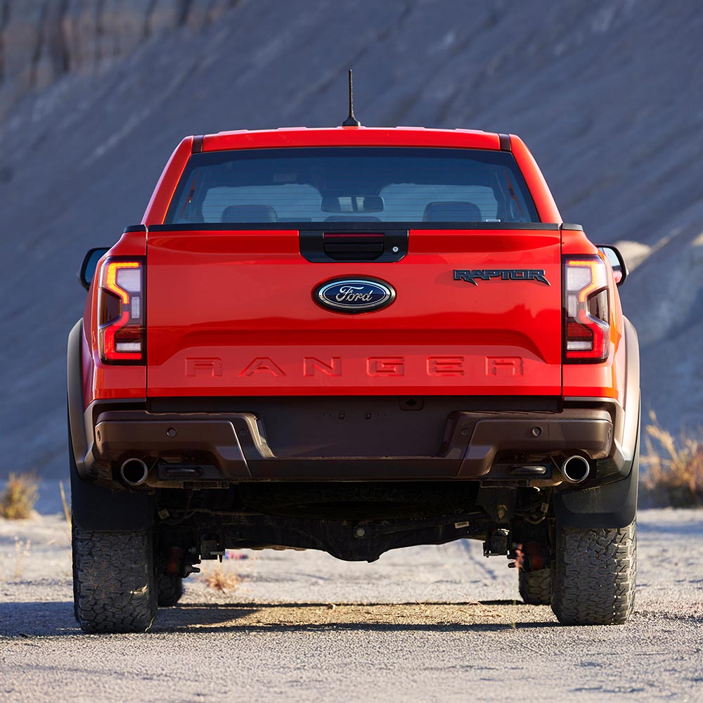 Vue arrière d’un Ford Ranger Raptor Code Orange garé à l’extérieur.