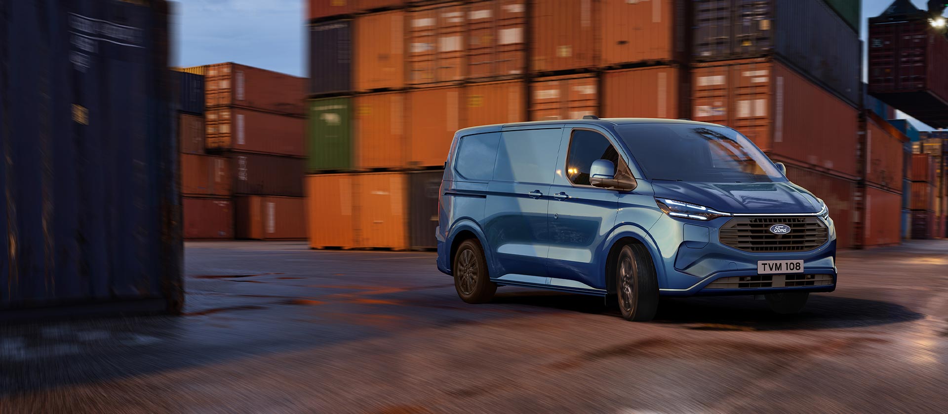 Un fourgon Ford Transit Custom hybride rechargeable bleu roule sur les quais d'un port.