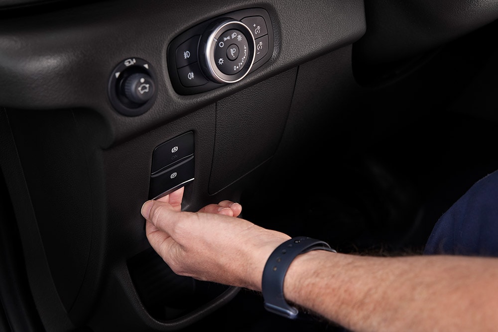 Gros plan d’une main appuyant sur un bouton du tableau de bord d’un fourgon électrique E-Transit Ford.