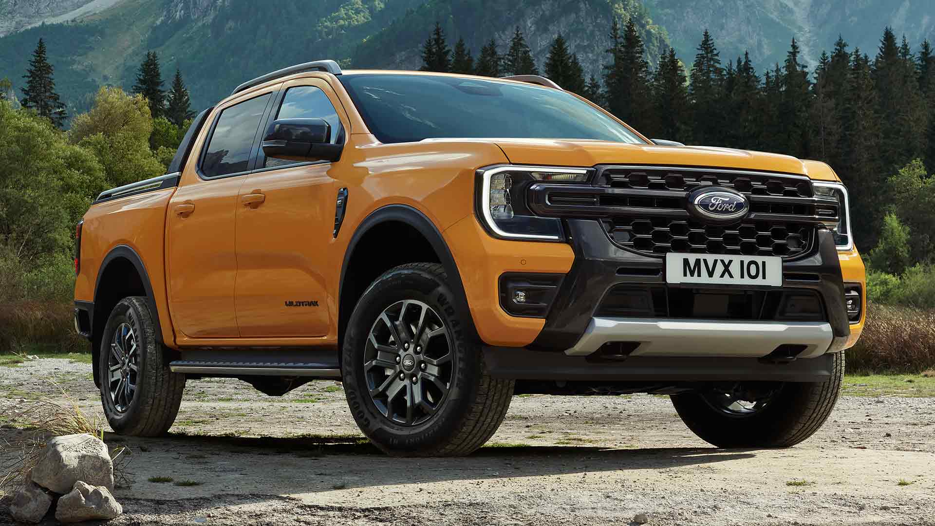 Ford Ranger Wildtrak Double Cabine jaune avec une forêt et des montagnes en arrière-plan.