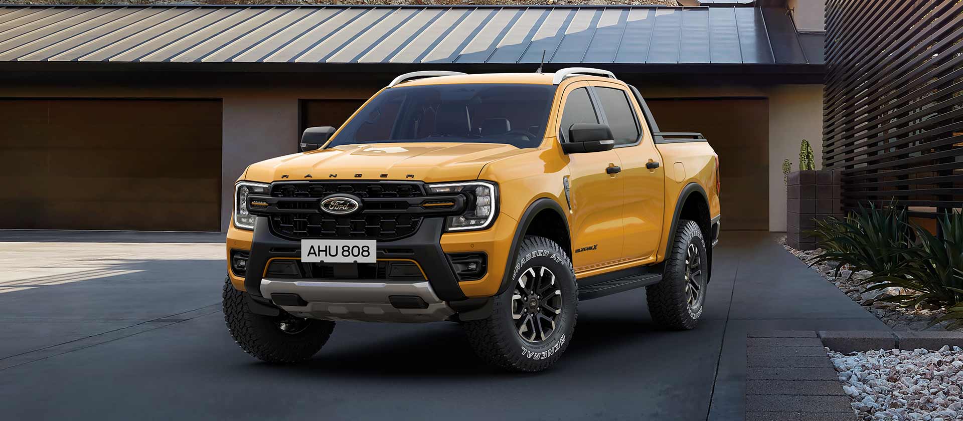 Ford Ranger Double Cabine jaune garé devant une maison.