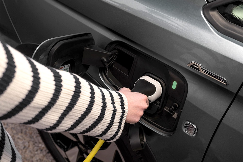 Une personne branche un câble de recharge sur un Ford Transit Connect hybride rechargeable.