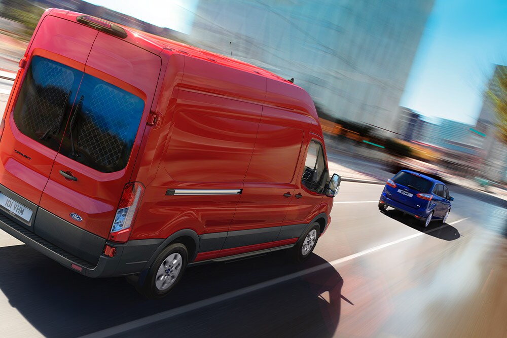 Fourgon Ford Transit rouge circulant sur une route.