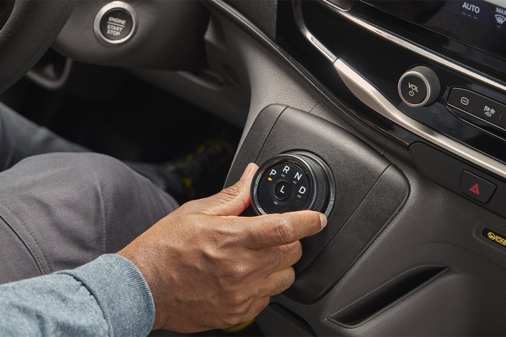 Main actionnant le levier de vitesse rotatif sur la console centrale du fourgon Ford Transit.