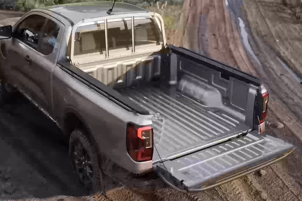 Vue de dessus d’un Ford Ranger XLT Super Cab argenté stationné sur une surface boueuse, hayon ouvert.