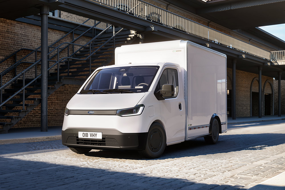 Fourgon châssis-cabine Ford Transit City® blanc stationné devant un bâtiment en briques.
