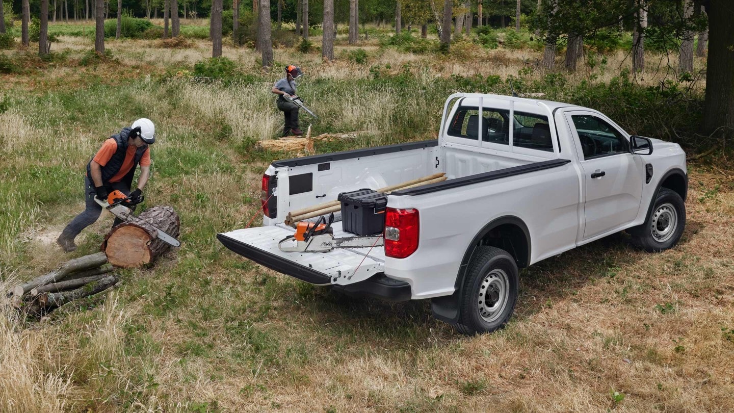 All-New Ranger in blue driving down forest road rear 3/4 view