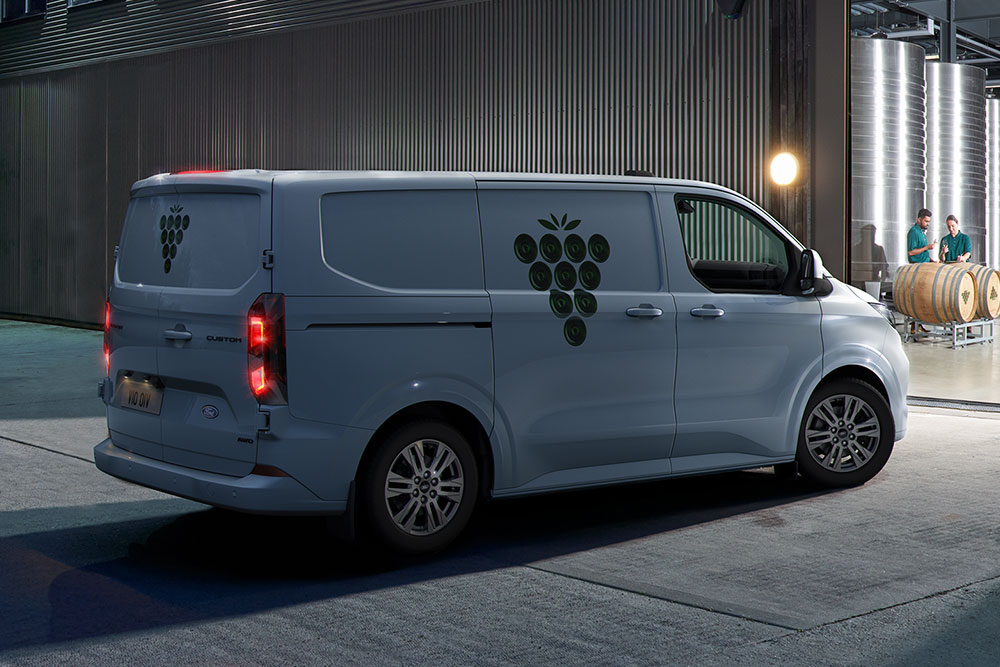 Un fourgon Ford blanc garé devant une porte d'entrepôt la nuit.
