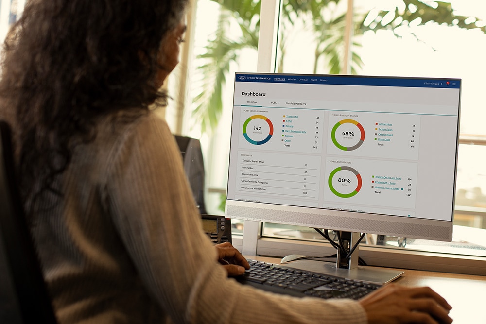 Femme consultant les données de son tableau de bord télématique Ford sur son ordinateur de bureau.