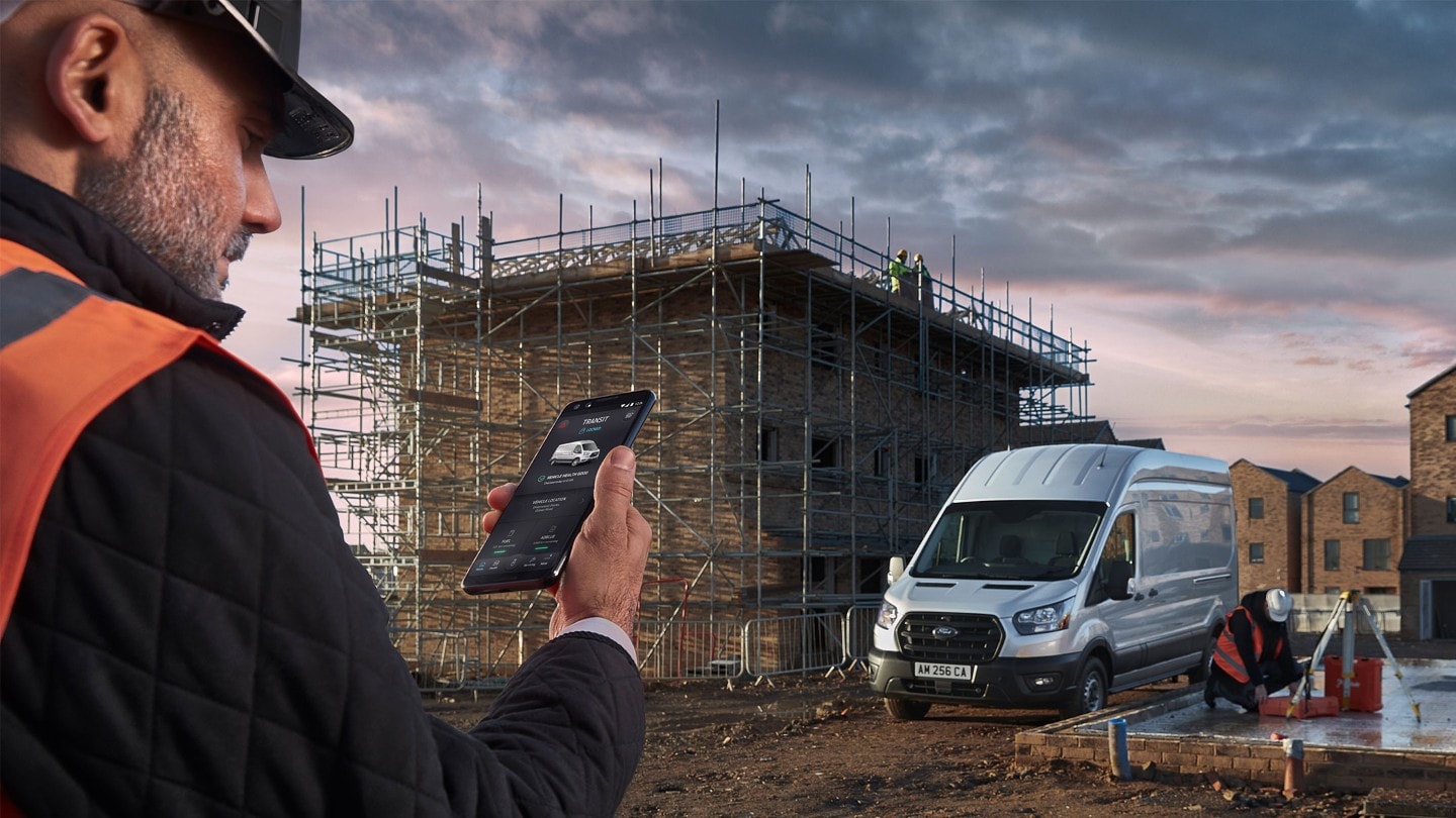 Building site with Ford Transit and worker checking his mobile phone