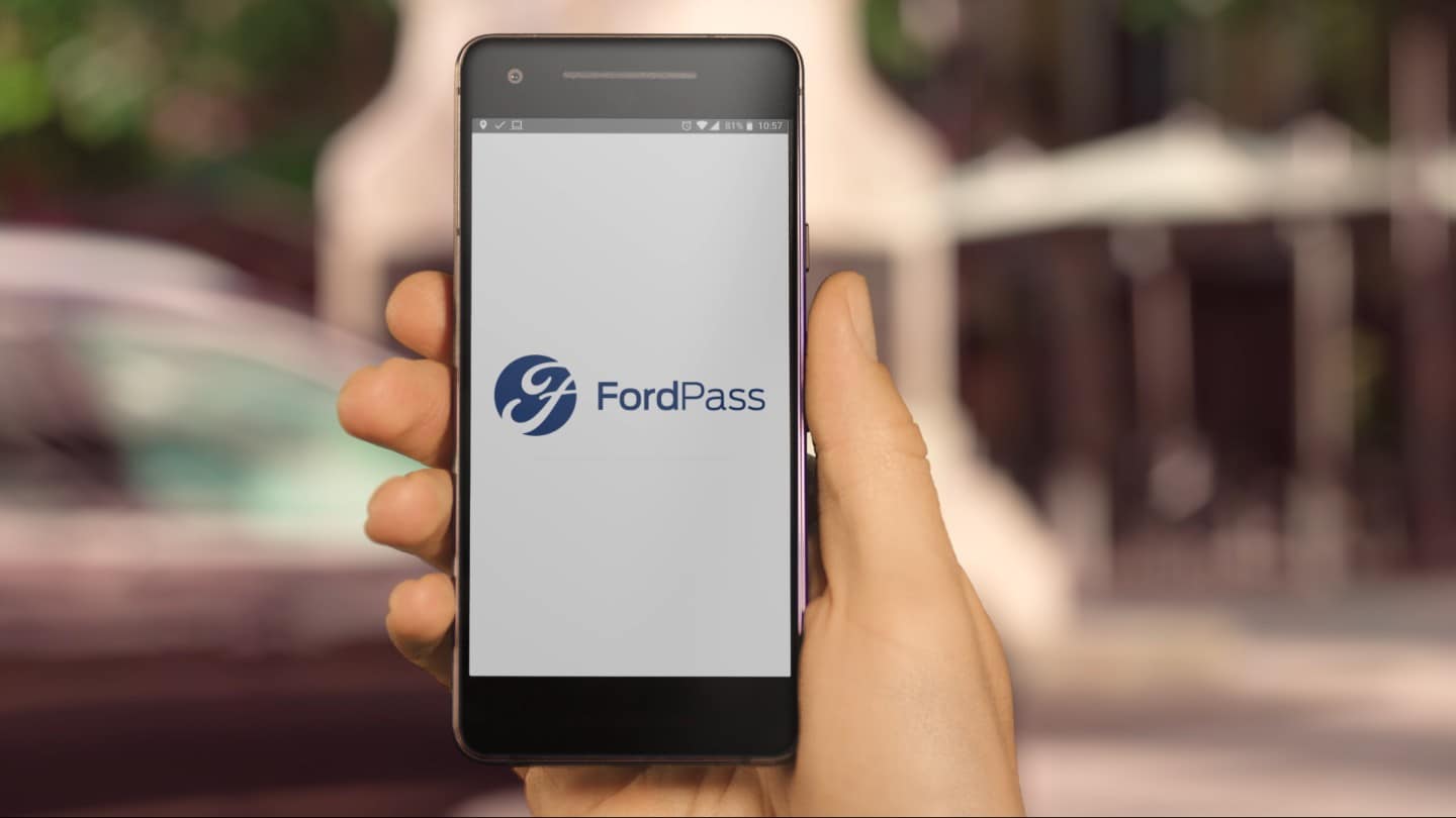 Main tenant un téléphone mobile affichant l’application FordPass.