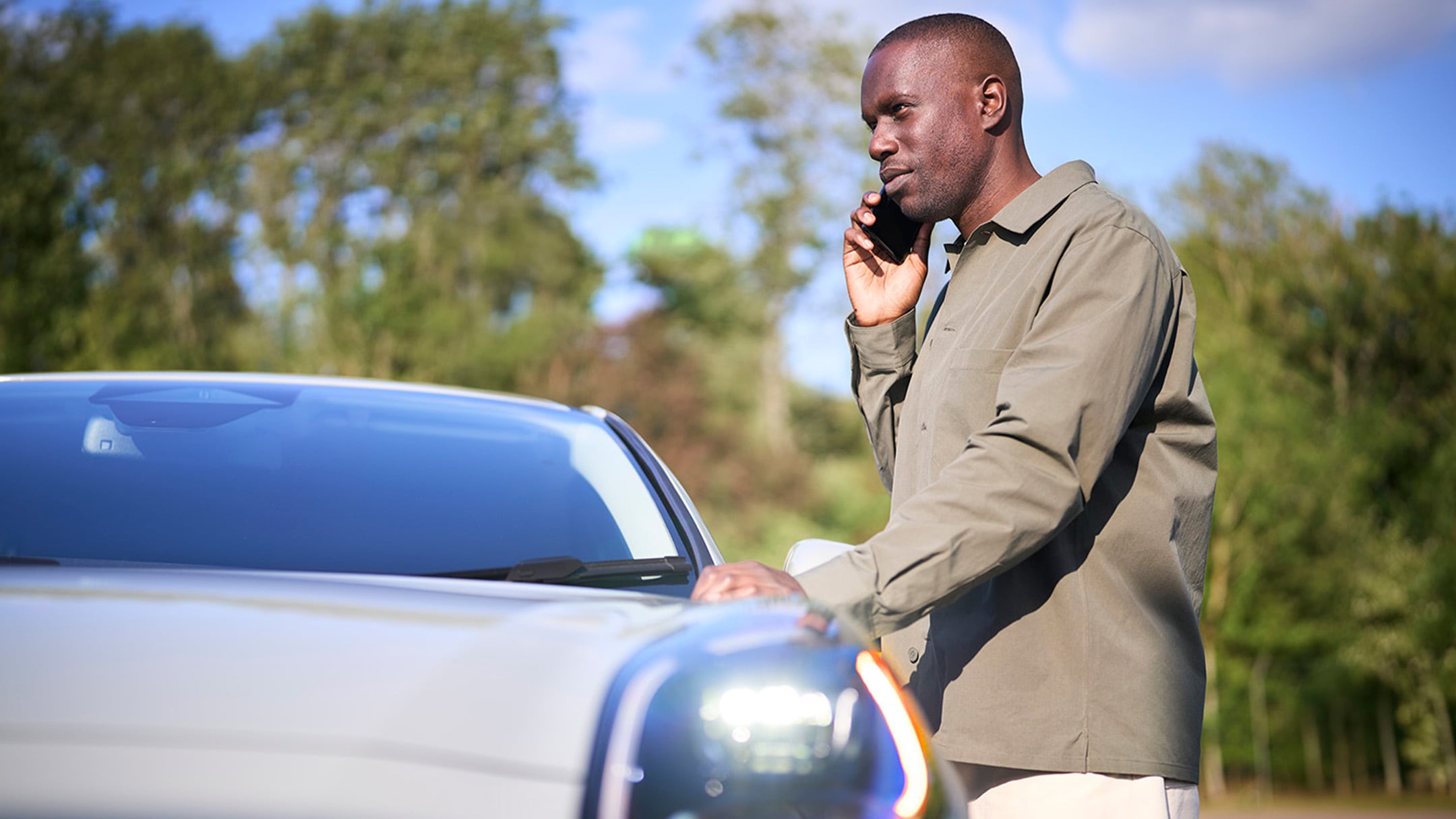 Une personne place un triangle de signalisation rouge près d'une voiture en panne sur le bord d'une route.​
