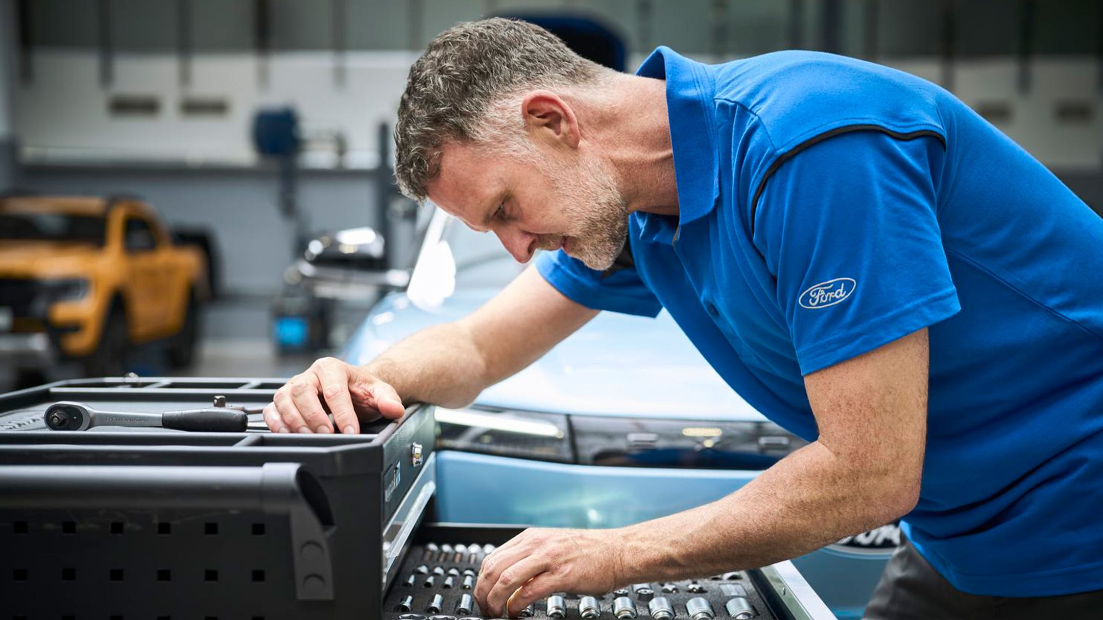Un expert Ford Pro, assis dans un véhicule, consulte un ordinateur portable pendant un entretien Ford.