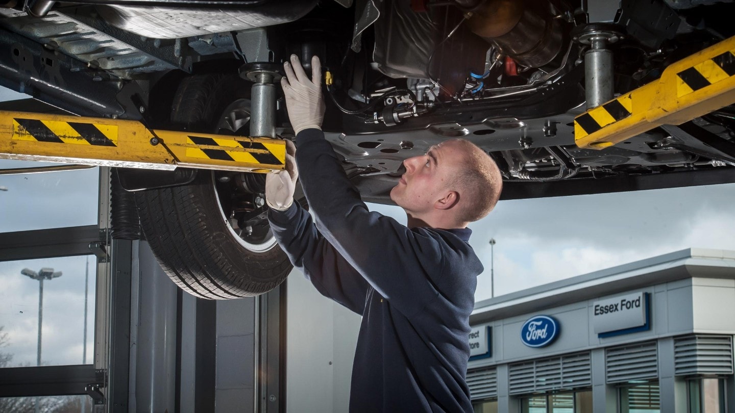 Un expert Ford effectuant une revision devant une concession. 