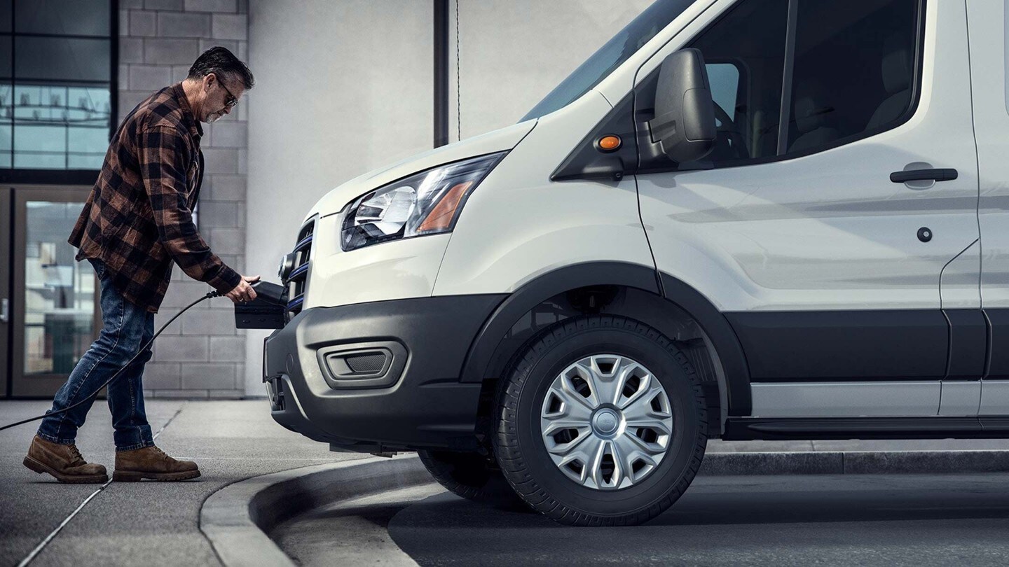 Un homme chargeant son Ford E-Transit à une borne de recharge publique.